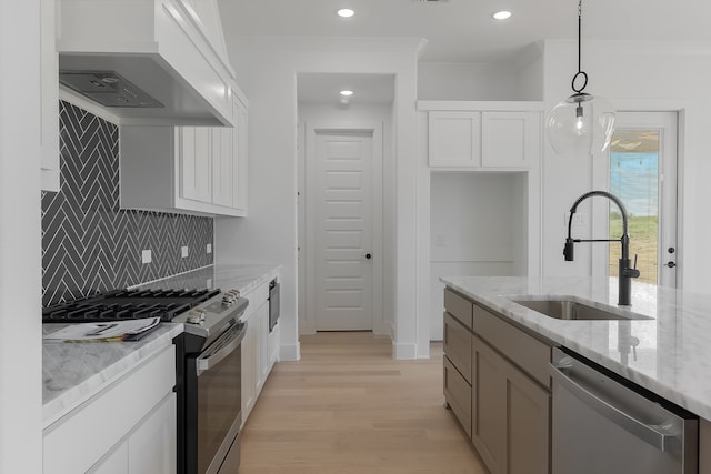 kitchen with stainless steel appliances, light stone countertops, sink, and white cabinets