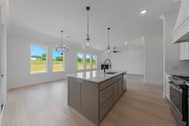 kitchen with white cabinets, a kitchen island with sink, light wood-type flooring, sink, and stainless steel appliances