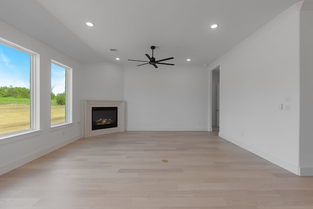 unfurnished living room with light hardwood / wood-style flooring, ornamental molding, and ceiling fan