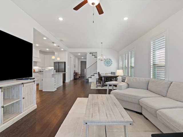 living room featuring dark hardwood / wood-style flooring, ceiling fan with notable chandelier, and vaulted ceiling