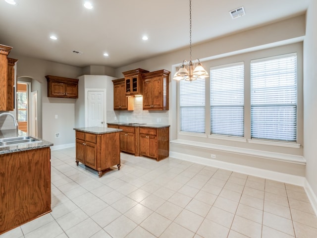 kitchen with dark stone countertops, sink, a center island, a chandelier, and tasteful backsplash