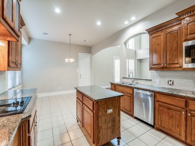 kitchen featuring decorative backsplash, a kitchen island, stainless steel appliances, sink, and light stone counters