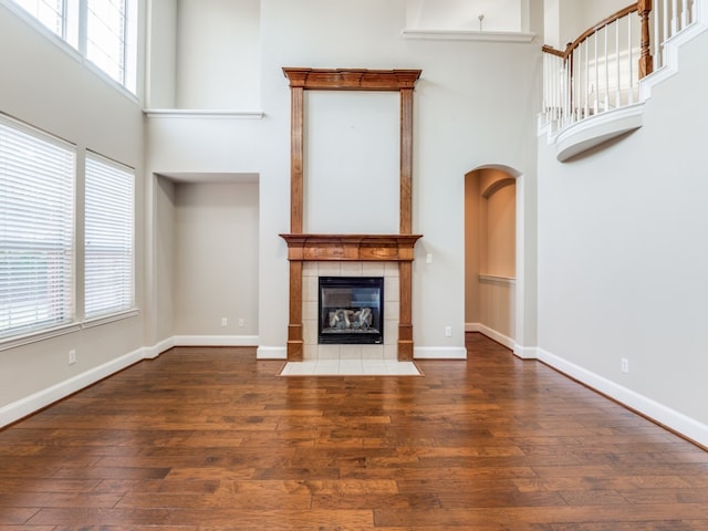 unfurnished living room featuring dark hardwood / wood-style floors, a towering ceiling, and plenty of natural light