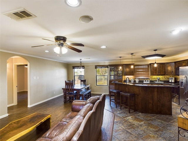 living room with dark wood-type flooring, ceiling fan, and ornamental molding