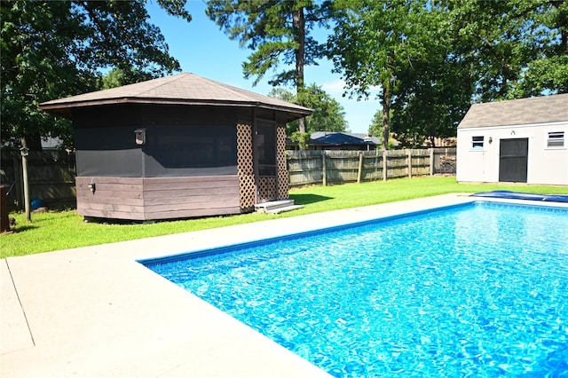 view of pool with a lawn and an outbuilding