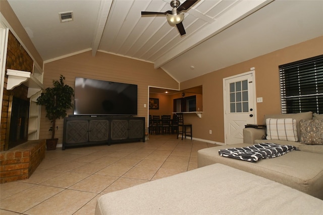 tiled living room with lofted ceiling with beams, a fireplace, and ceiling fan