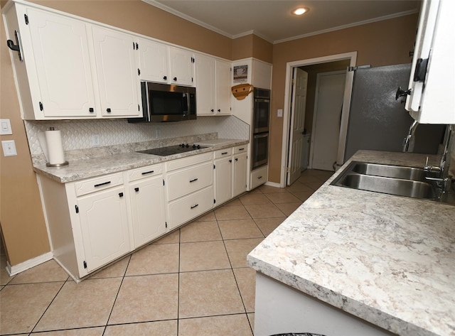 kitchen with appliances with stainless steel finishes, sink, white cabinetry, crown molding, and light tile patterned floors