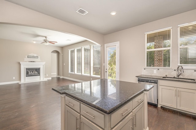 kitchen featuring sink, backsplash, stainless steel appliances, white cabinets, and dark stone counters