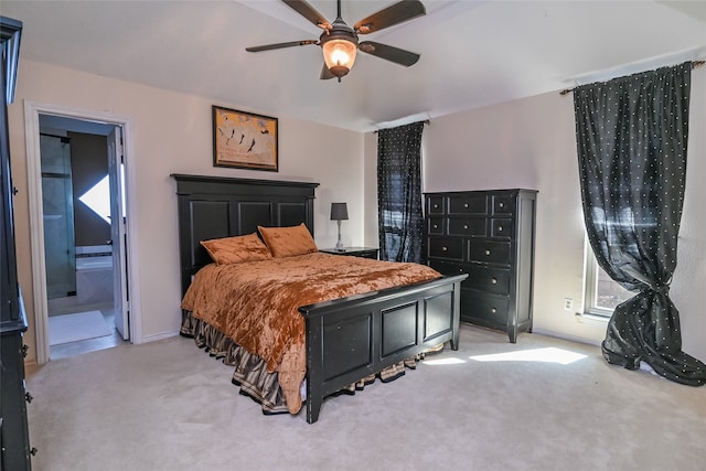 bedroom with ceiling fan, light colored carpet, and ensuite bath