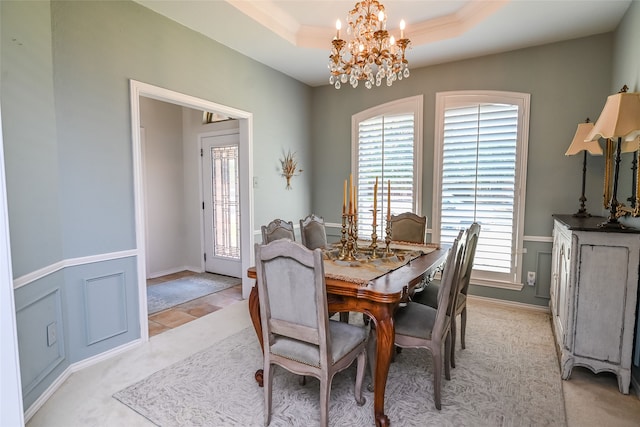 carpeted dining room with a notable chandelier, a healthy amount of sunlight, and a tray ceiling