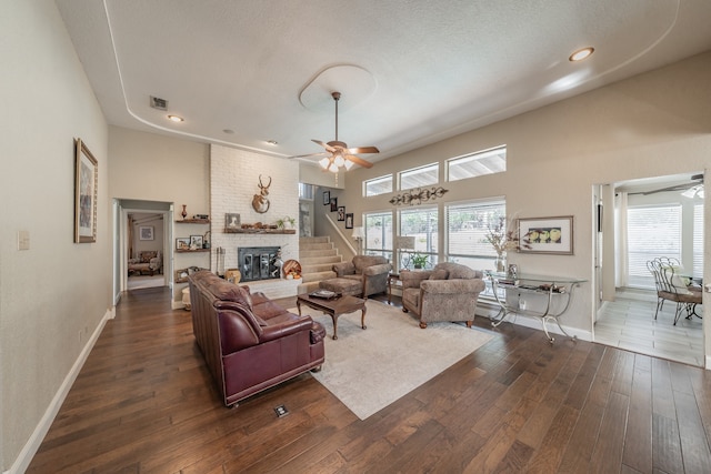 living room with dark wood-type flooring, ceiling fan, a textured ceiling, and a fireplace