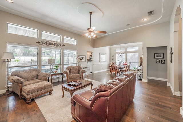 living room with dark wood-type flooring, ceiling fan, and a towering ceiling