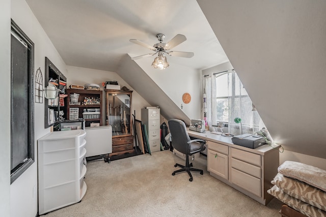 office featuring built in desk, vaulted ceiling, light carpet, and ceiling fan