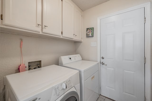 laundry area with independent washer and dryer, a textured ceiling, and cabinets