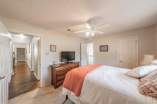 bedroom with ceiling fan, a textured ceiling, and hardwood / wood-style floors