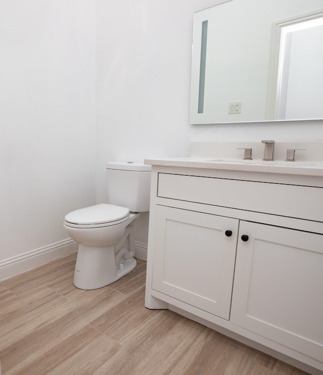 bathroom with toilet, vanity, and wood-type flooring