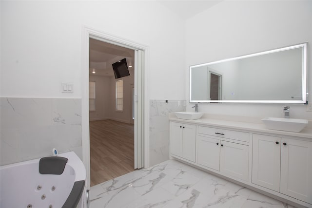 bathroom with vanity, tile walls, wood-type flooring, and a washtub