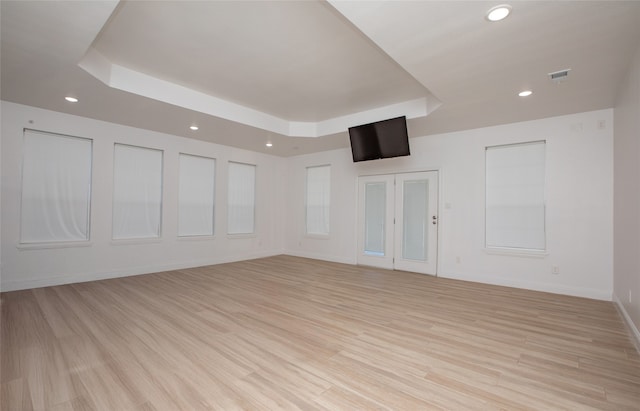 unfurnished room with light hardwood / wood-style flooring and a tray ceiling