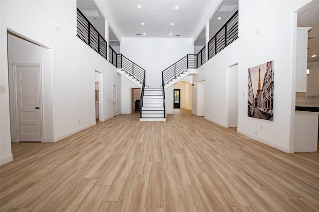 unfurnished living room with light hardwood / wood-style flooring and a high ceiling