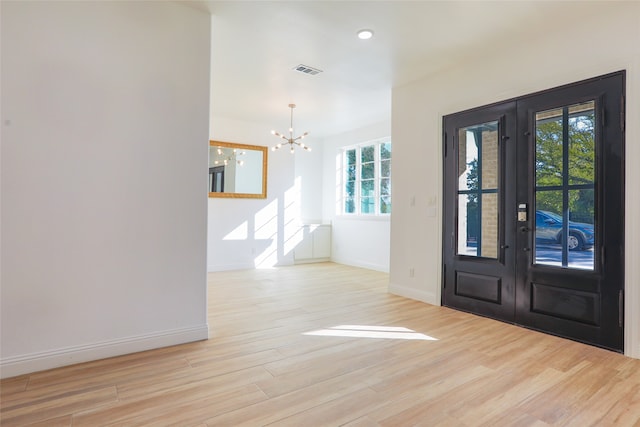 foyer featuring light hardwood / wood-style floors, french doors, a healthy amount of sunlight, and a chandelier