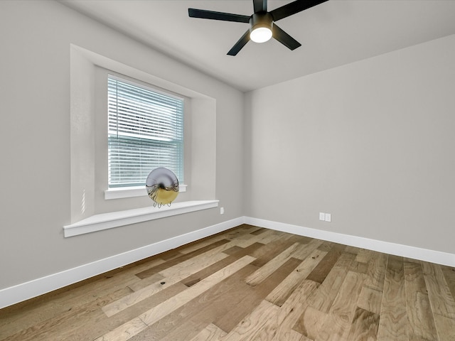 spare room with baseboards, ceiling fan, and light wood-style floors