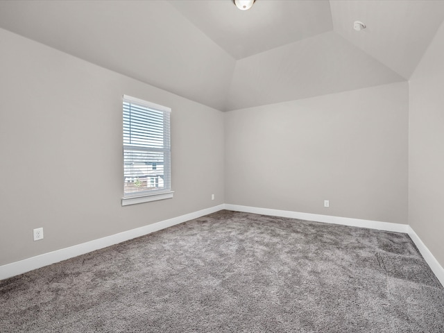 carpeted spare room with lofted ceiling and baseboards