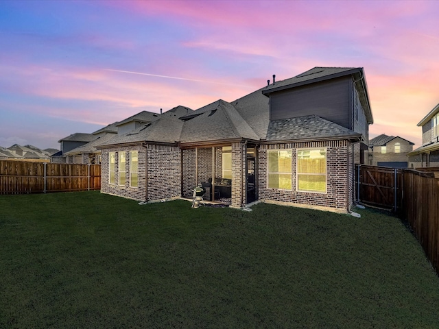 back house at dusk with a lawn