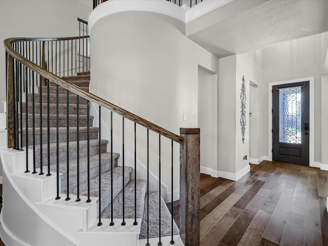 entryway featuring a textured ceiling, dark hardwood / wood-style floors, and a high ceiling