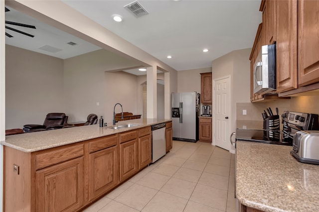 kitchen featuring light tile patterned flooring, stainless steel appliances, sink, and light stone counters