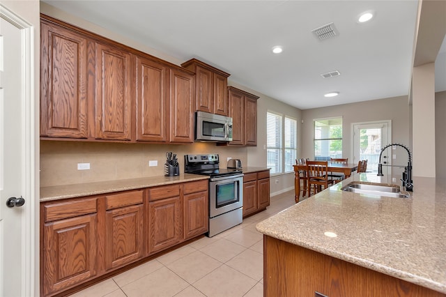 kitchen featuring light stone counters, stainless steel appliances, sink, and light tile patterned flooring