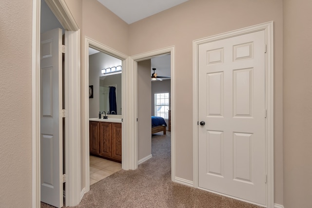 hallway featuring sink and light carpet