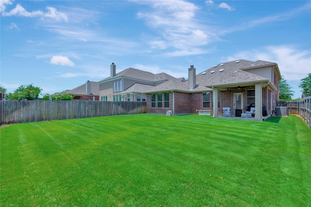 back of house with central AC, a yard, and a patio