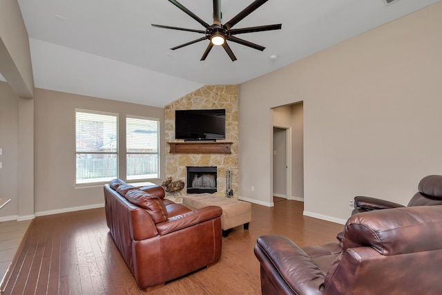 living room featuring lofted ceiling, a stone fireplace, wood-type flooring, and ceiling fan