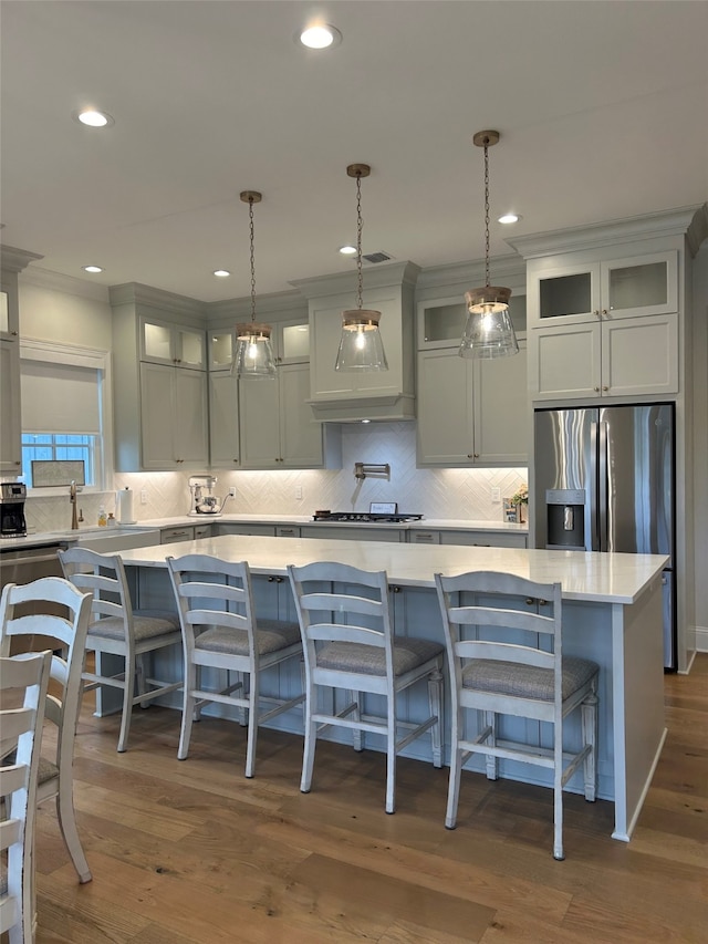 kitchen featuring dark wood-style floors, a kitchen island, light countertops, glass insert cabinets, and appliances with stainless steel finishes