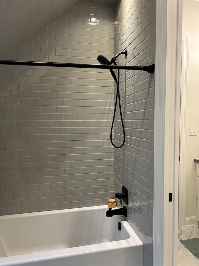 bathroom with tiled shower / bath and lofted ceiling