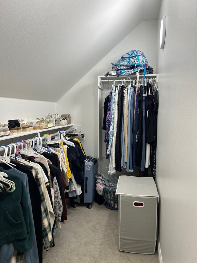 spacious closet featuring light colored carpet and vaulted ceiling