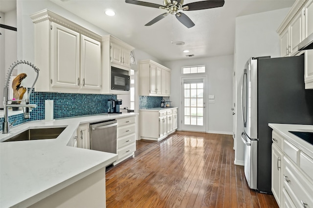 kitchen with decorative backsplash, white cabinetry, dark wood-type flooring, sink, and stainless steel appliances