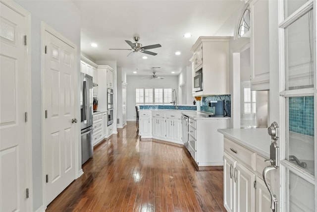 kitchen featuring stainless steel appliances, sink, dark hardwood / wood-style flooring, white cabinetry, and tasteful backsplash