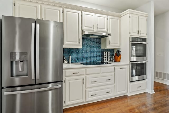 kitchen featuring backsplash, white cabinets, stainless steel appliances, and wood-type flooring