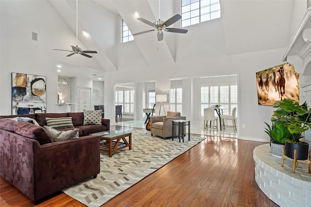 living room featuring light hardwood / wood-style flooring, ceiling fan, high vaulted ceiling, and plenty of natural light