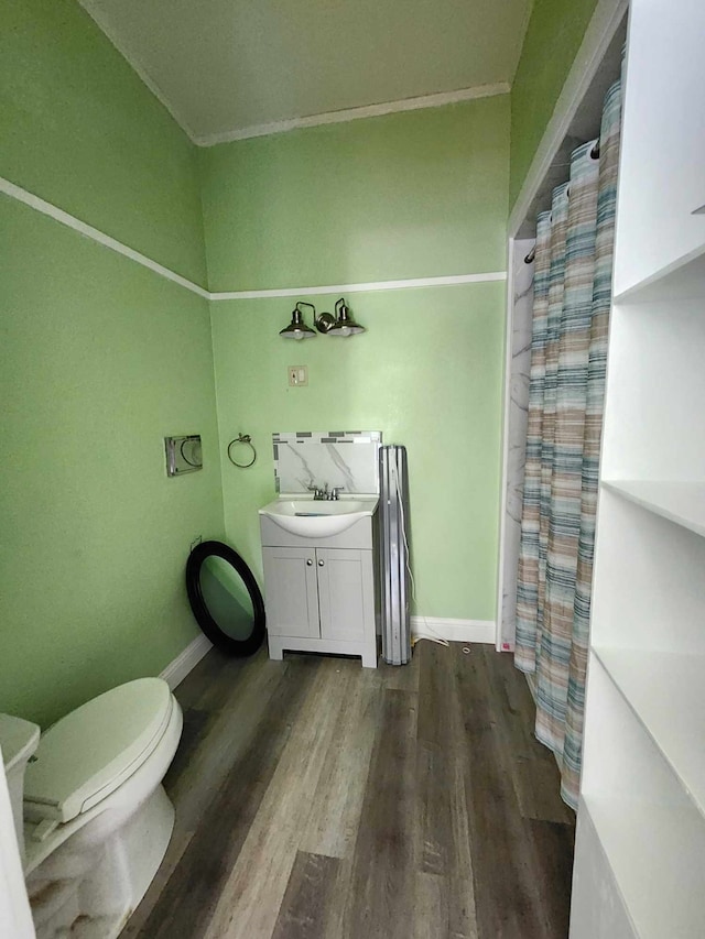 bathroom with vanity, ornamental molding, wood-type flooring, and toilet