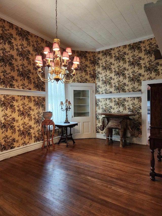 unfurnished dining area featuring dark wood-type flooring, crown molding, and a notable chandelier