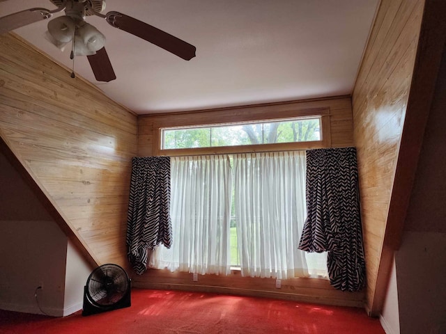 interior space featuring ceiling fan, wood walls, and lofted ceiling