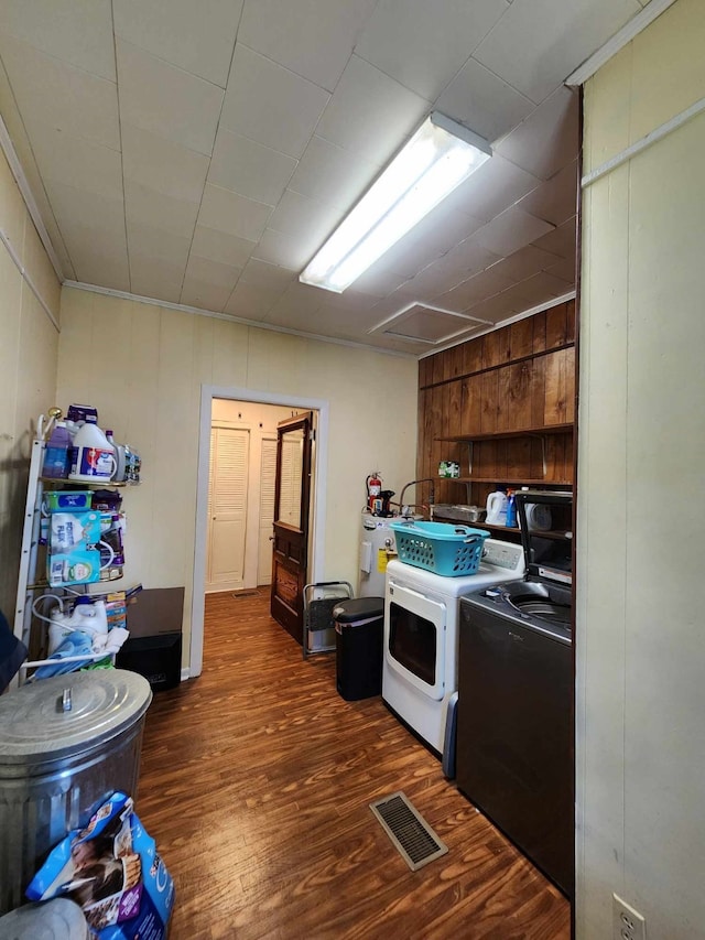 kitchen featuring washing machine and dryer, dark hardwood / wood-style floors, and wood walls