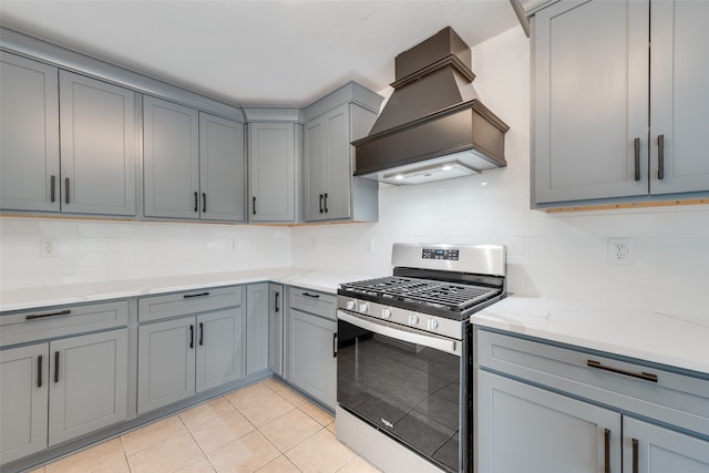 kitchen featuring custom range hood, gray cabinetry, backsplash, and stainless steel gas range