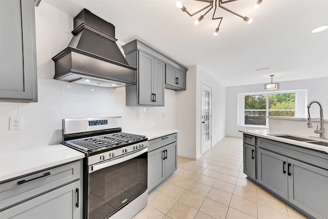 kitchen with sink, stainless steel gas stove, decorative light fixtures, gray cabinets, and premium range hood