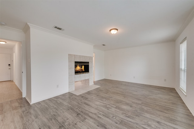 unfurnished living room featuring a tile fireplace, light wood-type flooring, and crown molding