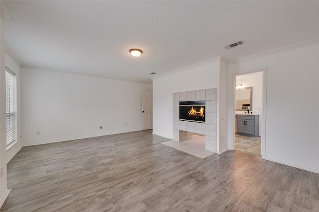 unfurnished living room featuring a fireplace, light wood-type flooring, and crown molding