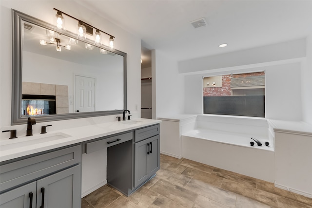 bathroom with a washtub, vanity, and a tile fireplace