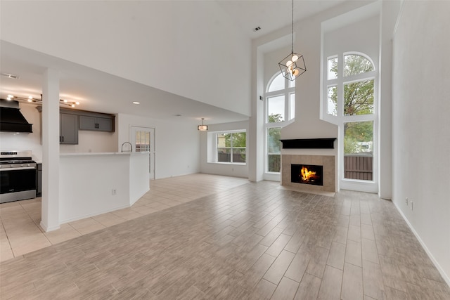 unfurnished living room with a towering ceiling, light wood-type flooring, plenty of natural light, and a fireplace